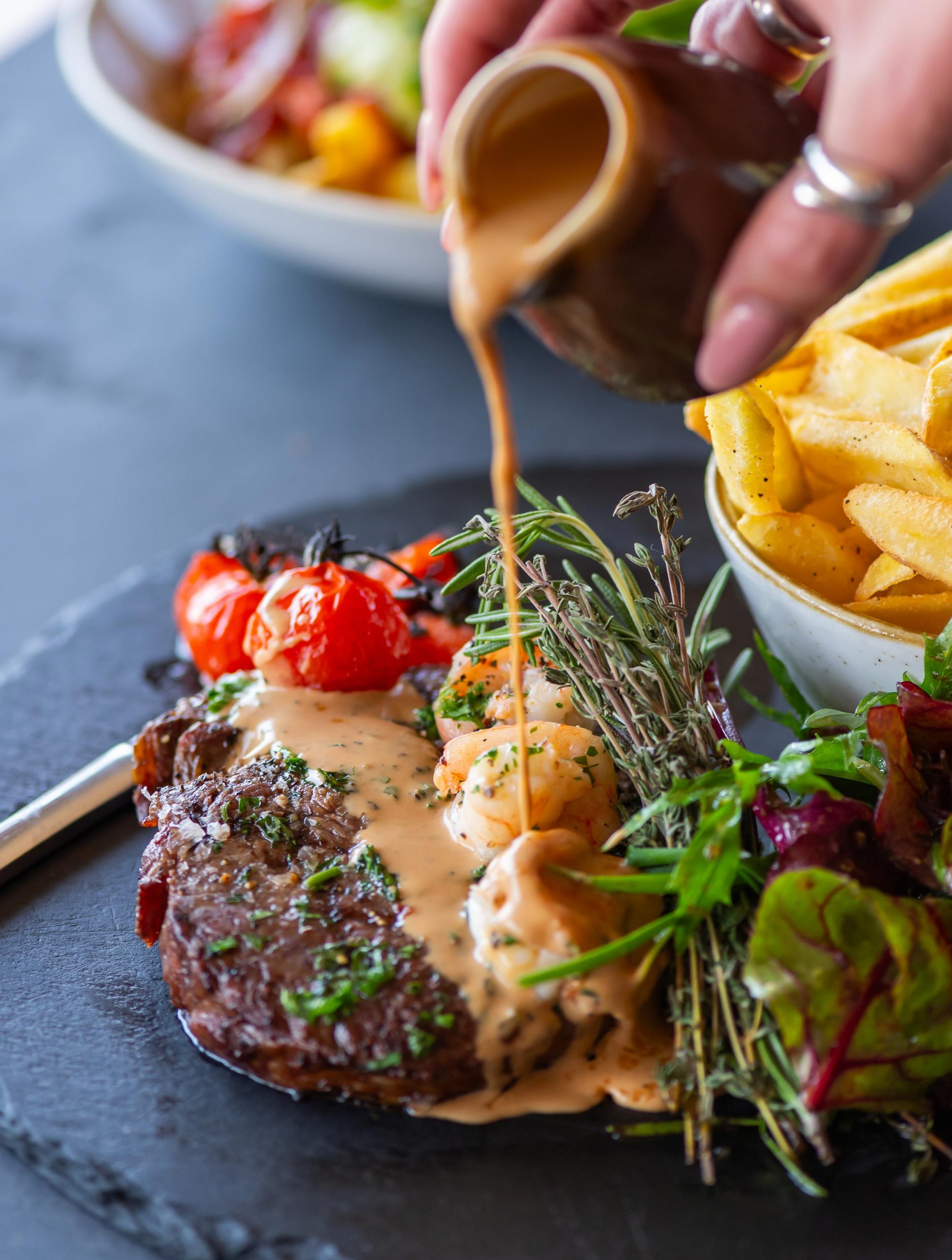 A steak dish with sauce being poured over it served at The Beachside Grill in Saunton, North Devon